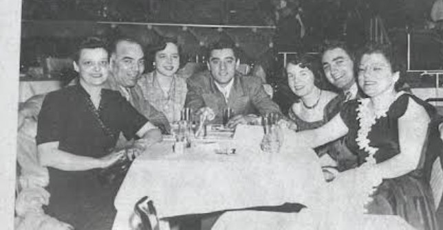 The family gathered around a restaurant table, decades ago